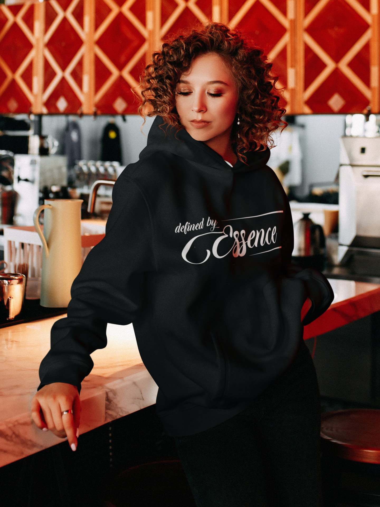 Women wearing a black infinite classic Defined by Essence hoodie while in the kitchen.
