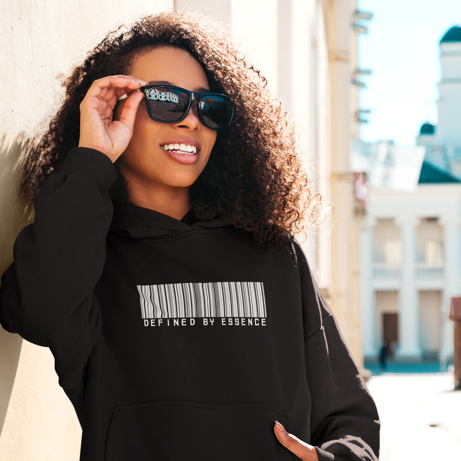 Women wearing a black barcoded Defined by Essence hoodie during a cool day outside.