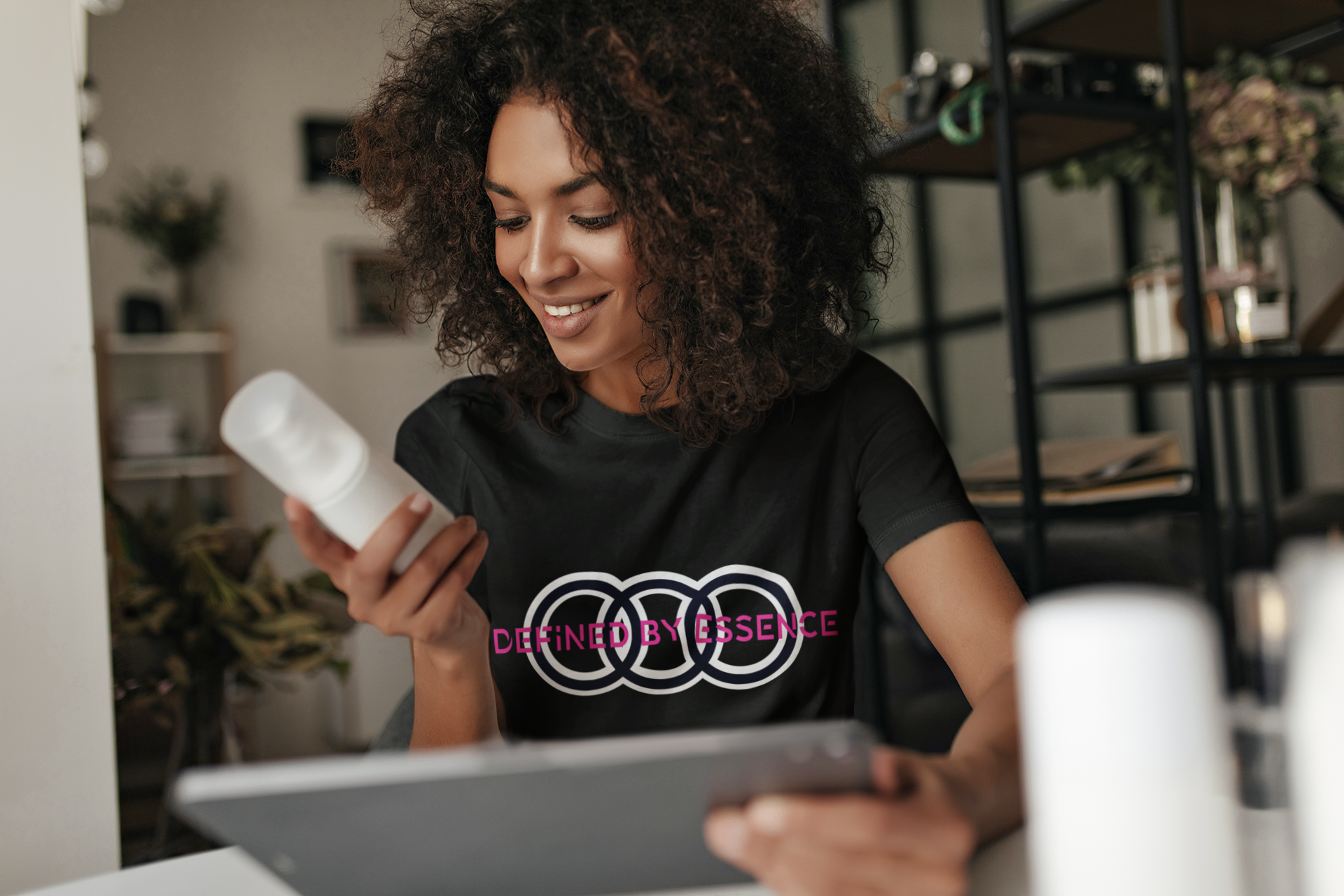 Women wearing a black Infinite Signature Defined By Essence T-Shirt looking at a product.